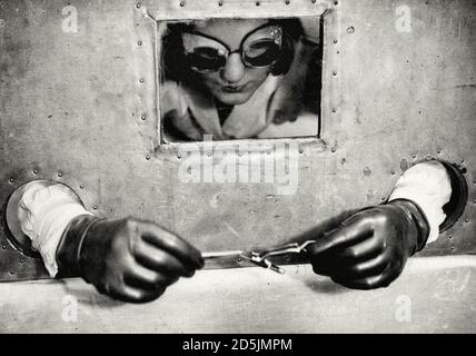 Retro photo of laboratory assistant behind a lead screen holds a test tube with 1 gram of radium, the Netherlands, 1932. Stock Photo