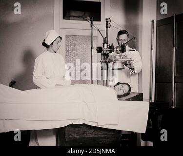 Archival photo of public hospital staff take an x-ray of a patient's head, USA, 1920. Stock Photo