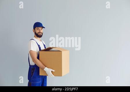 Smiling deliveryman holding cardboard parcel box in hands and looking at camera Stock Photo