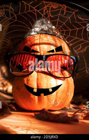Two Halloween pumpkins standing one on top of other and painted as Jack's lantern in bloody glasses and witch hat. Stock Photo