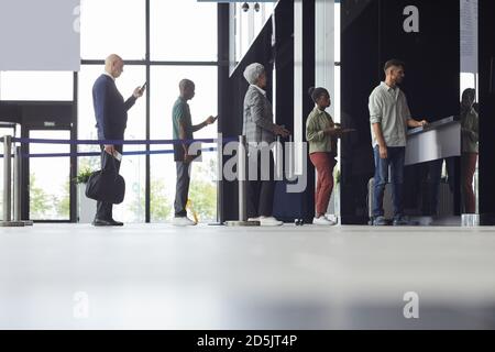 Group of people standing in a row and buying tickets for the plane at the airport Stock Photo