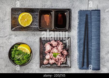 Traditional japanese or seafood concept. Delicious and healthy boiled mini octopus and wakame or seaweed salad with soy sauce and lemon served with Stock Photo