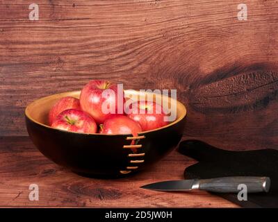 Red apples in a dark brown bowl, on wooden backdrop Stock Photo