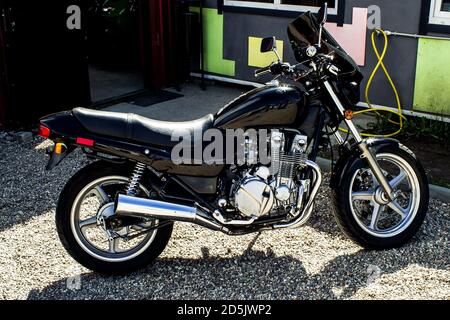 Black sports motorcycle, photo bike on the side on a sunny day with a chromed engine and parts. Beautiful road motorbike with black safety glass. clos Stock Photo