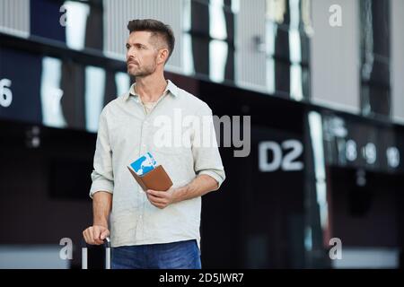 Young man with tickets and luggage waiting for his flight he going to business trip Stock Photo
