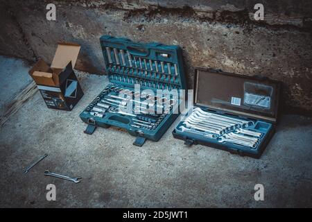 Professional mechanic tool kit in a box for repairing motorcycles and equipment. Closeup chrome steel tool on concrete in a garage. Collection of diff Stock Photo