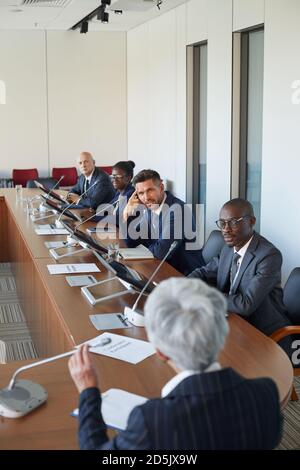 Business team sitting at the table and listening to businesswoman at conference Stock Photo