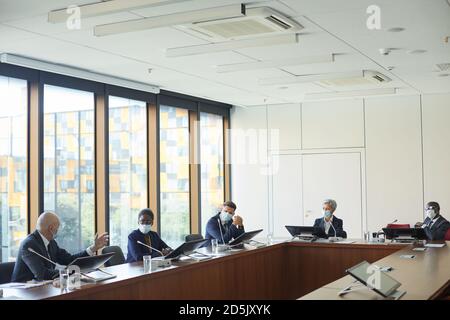Group of business people in protective masks sitting at the table during conference at board room Stock Photo