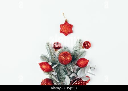 Christmas composition of spruce and eucalyptus branches decorated with red Christmas ornaments balls, cones and star on white background. Stock Photo