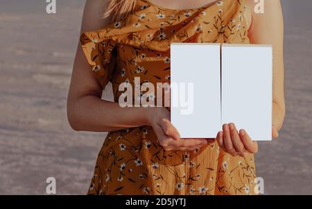 Girl in a yellow dress holds two isolated white boxes in her hands Stock Photo