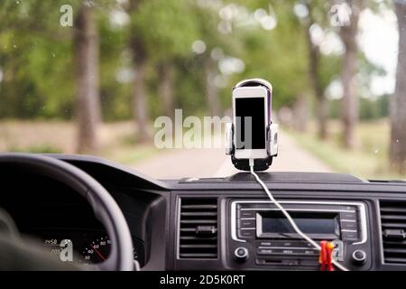Mobile phone with GPS card in the car. A white smartphone on a stand in the car is used for navigation. Stock Photo