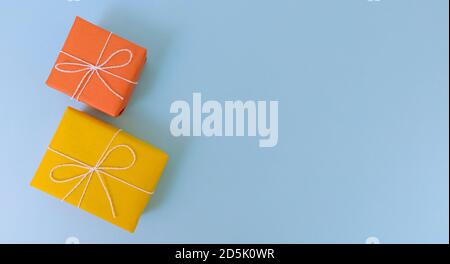 Yellow and orange gift boxes on a blue background. Simple flat lay with copy space. Stock Photo
