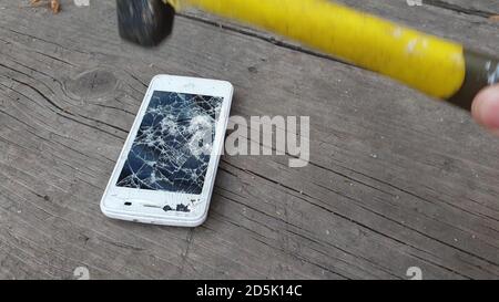 hammer smashes smartphone screen, recycling old and broken electronics Stock Photo