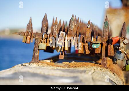 Group of rusty locks on a seafront railing in a sunny day Stock Photo