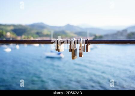 Seven rusty locks on a seafront railing in a sunny day Stock Photo