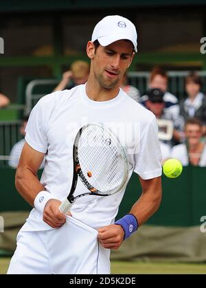 Serbia's Novak Djokovic catches the ball in his pocket during practice on day twelve of the 2011 Wimbledon Championships at the All England Lawn Tennis and Croquet Club, Wimbledon. Stock Photo