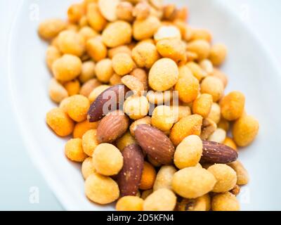 Closeup shot of nuts and snacks placed on a white plate Stock Photo