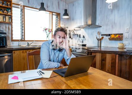 Stressed business man on laptop working from home looking worried, tired and overwhelmed. Exhausted entrepreneur working remotely during social distan Stock Photo