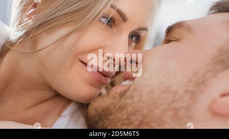 Happy Young Couple Cuddling Together in the Bed, Smiling and Looking at Each Other. Blonde Female and Her Fit Loving Partner Experiencing Tender and Stock Photo