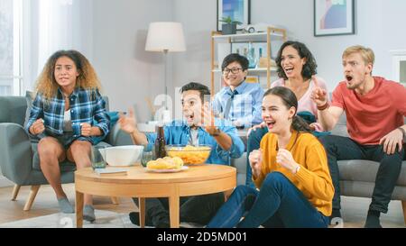 At Home Diverse Group of Sports Fans Sitting on a Couch Watching Important Sports Game Match on TV, They Cheer for the Team at a Very Tense Moment Stock Photo