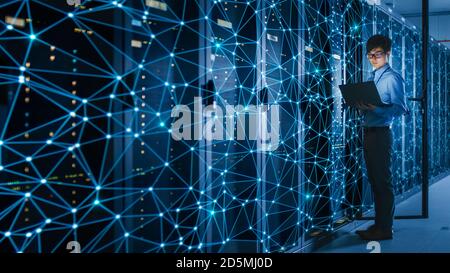 Shot of a Asian IT Engineer Using Laptop in a Data Center Server Room. Concept of Internet Web Visualization Projection with Blue Lines on Server Rack Stock Photo