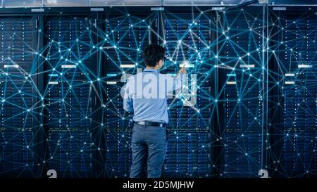 Internet Web Concept. Shot In the Modern Data Center: IT Engineer Standing Beside Open Server Rack Cabinets and Touching Digital Connections on a Stock Photo