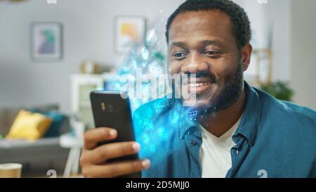 Visual Effect of Connecting and Surfing the Web with Illustrative Icons and Symbols. Handsome Black Man Uses Smartphone in His Living Room. Browsing Stock Photo