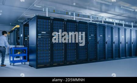 In the Modern Data Center: Team of IT Technicians Working with Server Racks, Running Maintenance and Diagnostics, Checking Networking and Cloud Stock Photo
