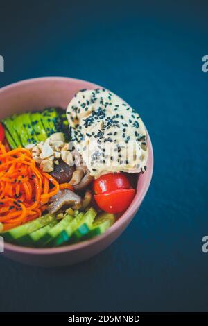 Delicious poke bowl dish served for lunch in Asian restaurant.Traditional Hawaiian cuisine dish with fresh avocado,cucumbers,hummus,korean carrots & m Stock Photo