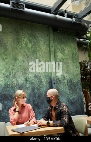 Young people in protective masks have a business meeting at the restaurant Stock Photo
