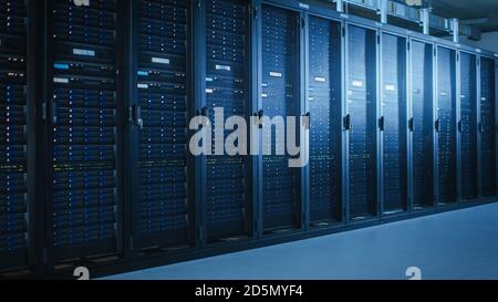 Shot of Modern Data Center With Multiple Rows of Fully Operational Server Racks. Modern High-Tech Telecommunications Database Super Computer in a Room Stock Photo