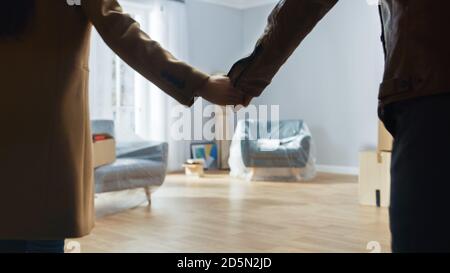 Excited Young Couple Holding Hands Enters Newly Purchased / Rented Apartment. Bright Modern Home for Happy Young People. Stock Photo