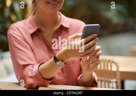 Close-up of young woman typing online message on her smartphone Stock Photo