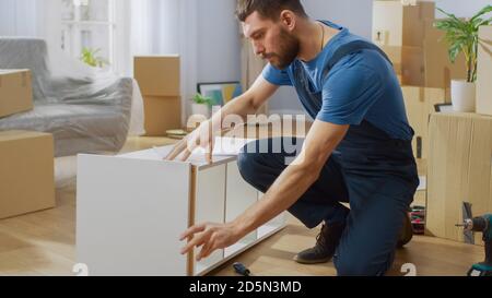 Furniture Assembly Worker Assembles Bookshelf. Professional Handyman Doing Assembly Job Well, Helping People who Move into New House. Stock Photo
