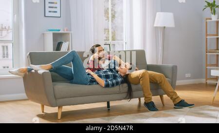 Happy Young Couple is Lying on a New Couch in the Living Room and Having a Rest. Bright Modern Apartment with Stylish Furniture. Stock Photo