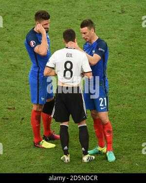 France's Laurent Koscielny (right) and Olivier Giroud (left) console Arsenal team-mate Germany's Mesut Ozil Stock Photo