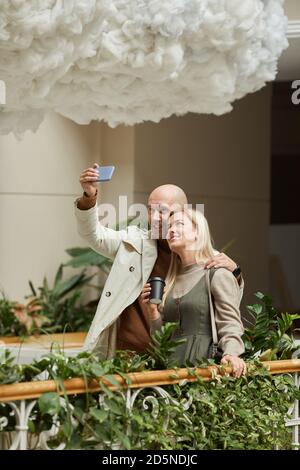 Man making selfie portrait on the mobile phone with young woman during their date on the balcony Stock Photo
