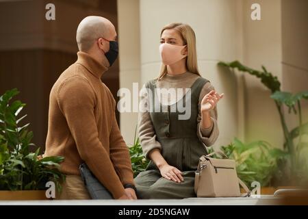 Young couple in protective masks talking to each other they keeping social distancing Stock Photo