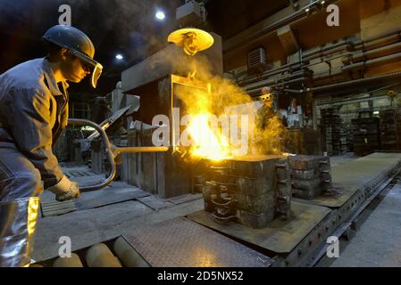 workers in a foundry casting a metal workpiece - safety at work and teamwork Stock Photo