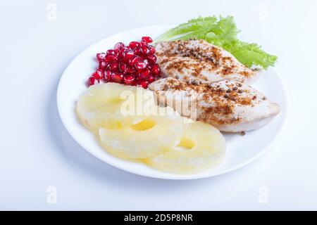 Fried chicken fillets with lettuce, pineapple and pomegranate seeds isolated on white background, close up. Stock Photo