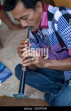 Vertical shot of a musician playing with emotion a traditional flute during a wedding preparation, South Sulawesi, Indonesia Stock Photo