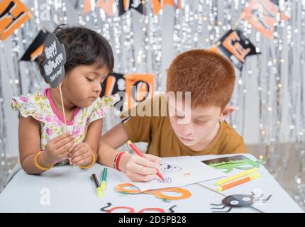 Selective focus on drawing hands, Kids busy in making or drawing halloween props - concept of halloween, holiday and childhood festival celebration Stock Photo