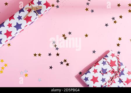 Congratulation Christmas postcard from mock-up festive gift boxes and shiny star confetti decoration on a pastel pink background with shadows, copy sp Stock Photo