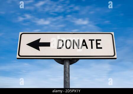 Donate sign. White street signs with arrow on metal pole with word. Directional road. Crossroads Road Sign, Arrow. Blue sky background. Charity. Stock Photo