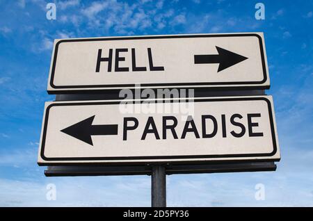 Hell versus paradise road sign. White two street signs with arrow on metal pole with word. Directional road. Crossroads Road Sign, Two Arrow. Stock Photo
