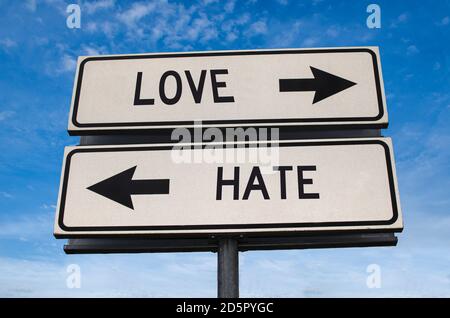 Love versus hate road sign. White two street signs with arrow on metal pole with word. Directional road. Crossroads Road Sign, Two Arrow. Blue sky bac Stock Photo