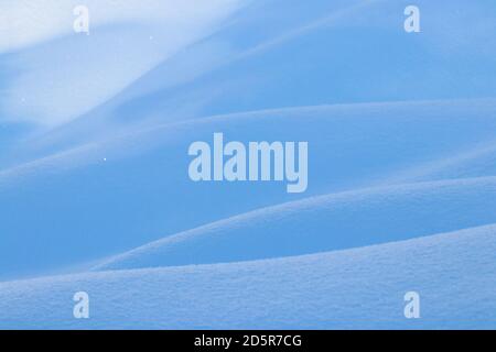 beautiful smooth lines texture of snowdrifts play of light and shadow of a winter landscape on the background Stock Photo