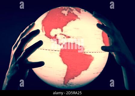 Hands holding a globe with red continents
