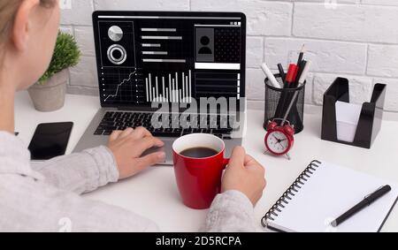 Female financial analyst working on laptop at office, studying statistics graphs Stock Photo