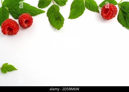 Three ripe raspberries isolated on white background close-up. Beautiful red fresh raspberries with leaves along the contour on the table. Top view. Ba Stock Photo